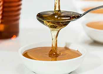 maple syrup being poured into spoon and bowl
