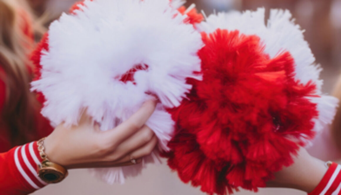 two cheerleaders holding pom poms together
