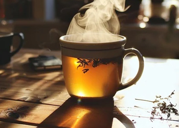 hot cup of tea, steaming on wooden table