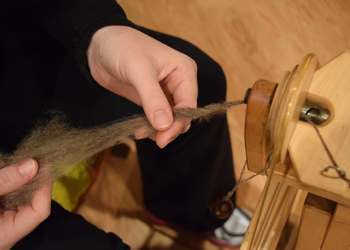 close up of hand holding yarn spun on spinning wheel